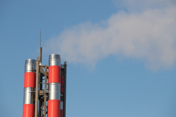 Big blue chimney gives white steam in the blue sky