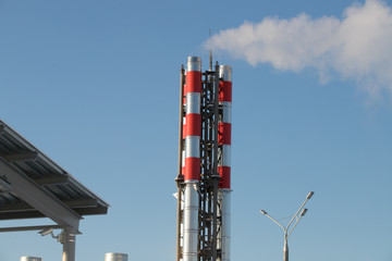 Big blue chimney gives white steam in the blue sky