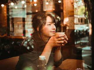 Naklejka premium Asian woman drinking coffee in coffee shop cafe