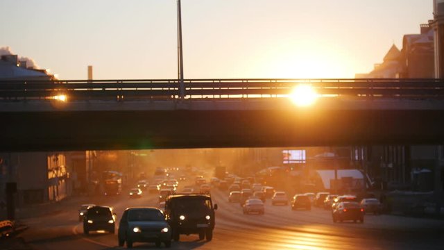 Cars riding on the road under the bridge. Sunset.