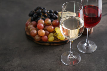 Glasses with different kinds of wine and snacks on grey table