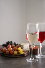 Glasses with different kinds of wine and snacks on grey table