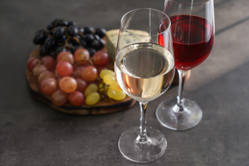 Glasses with different kinds of wine and snacks on grey table