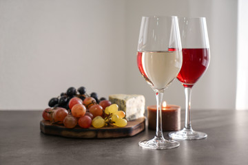 Glasses with different kinds of wine and snacks on grey table