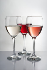 Glasses with different kinds of wine on grey table