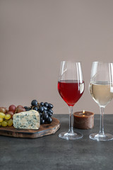 Glasses with different kinds of wine and snacks on grey table