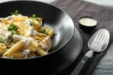 Plates with tasty penne pasta and cream sauce on table