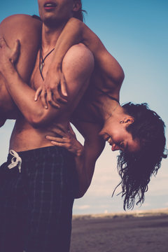 young couple play and have fun at the beach - outdoor love relationship people joking - man carry the girl on his body - beautiful people enjoy vacation summer time