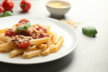 Plate with tasty penne pasta on grey table
