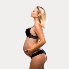 Obraz premium Blonde pregnant woman in underwear on isolated grey background