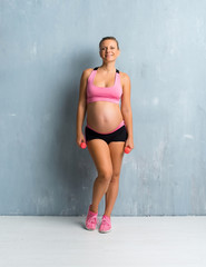 Fototapeta premium Blonde pregnant woman doing sport making weightlifting
