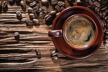 cup with coffee on vintage wood board and beans.
