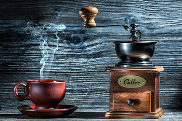 vintage wooden coffee mill and brown cup with steam.