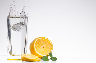 A glass of lemonade on a light background with splashing water