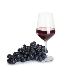 Glass of red wine with ripe grapes on white background