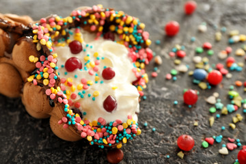 Delicious sweet bubble waffle with sprinkles on grey background