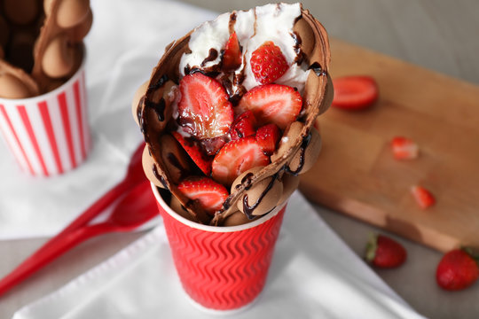 Delicious sweet bubble waffle in cup on table
