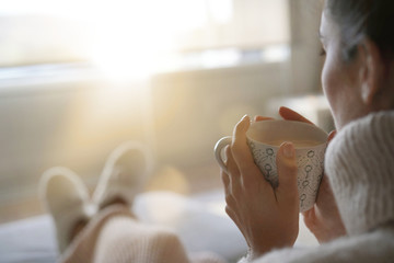 Cosy brunette at home on couch with hot drink