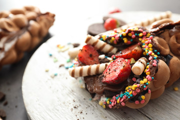 Delicious bubble waffle on wooden board, closeup