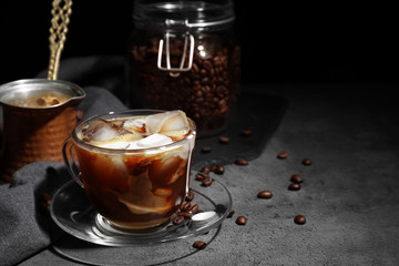 Glass cup of cold coffee on grey table