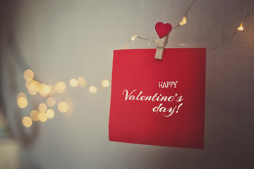happy Valentine's day inscription on a red piece of paper. sheet hanging on the clothespin with a heart.
