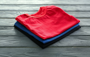 Stack of colorful t-shirts on wooden background