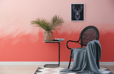 Comfortable armchair with table near pink wall