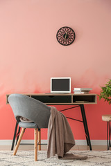 Comfortable workplace near pink wall