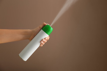Woman spraying air freshener on color background