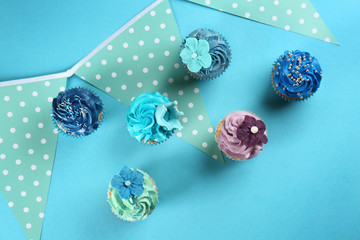 Delicious cupcakes with party decor on color background