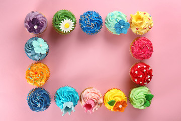 Frame made of delicious cupcakes on color background