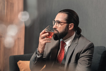 Successful man wearing nice hand watch holding glass of whisky