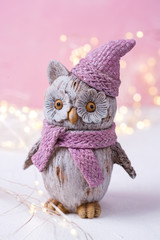 Decorative toy bird owl and fairy lights on bright  pink wooden  background.