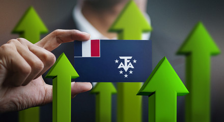 Nation Growth Concept, Green Up Arrows - Businessman Holding Card of French Southern Flag