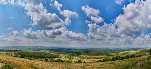 Fototapeta na wymiar Panorama of a beautiful cloudy sky over the fields.
