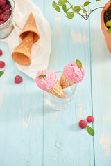 Homemade raspberry ice cream in waffle cones on rustic wooden background, selective focus. Summer time