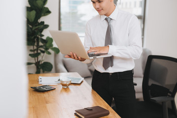 Young asian businessman holding a laptop pc.