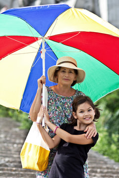Happy grandmother and granddaughter with big colorful umbrella