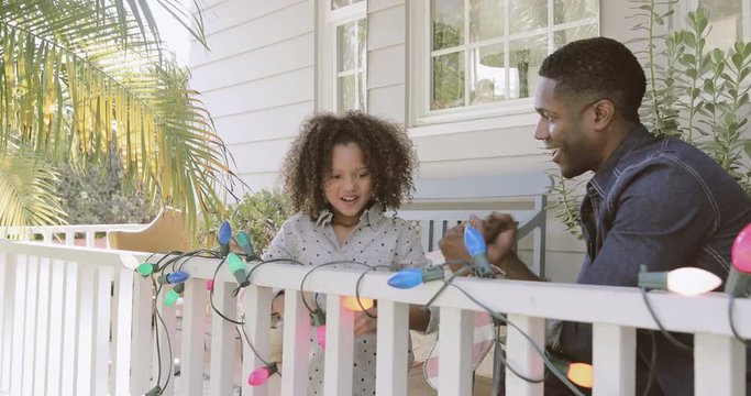 African American Father And Daughter Turning On Christmas Lights Outdoors