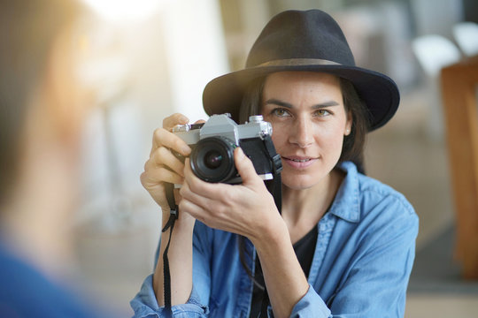   Trendy stunning brunette taking photos of model with vintage camera