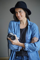  Trendy stunning brunette on isolated grey background with vintage camera