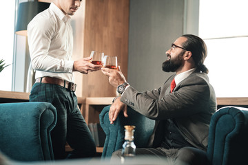Young employee joining his boss in the restaurant drinking whisky