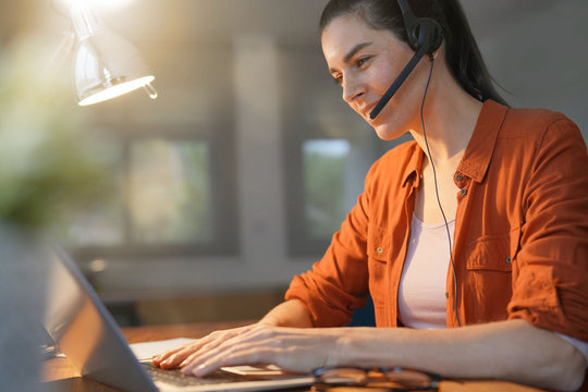  Stunning brunette working on computer at home with headset