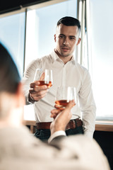 Young handsome man drinking some alcohol with his boss