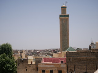 Obraz premium Panorama of the old town in Fez, Morocco, with the tower of a Mosque over the roofs of brown houses in an Arabic medina 