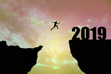 Man jumping 2019. man jumping over cliff on sunset background,Business concept idea