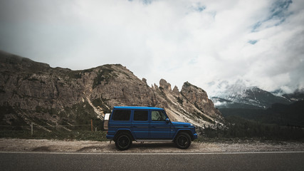 G-Wagon in Italy standing beside the road with mountains - obrazy, fototapety, plakaty