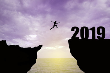 Man jumping 2019. man jumping over cliff on sunset background,Business concept idea