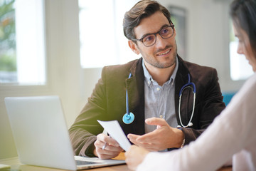  Modern young doctor speaking to patient in office