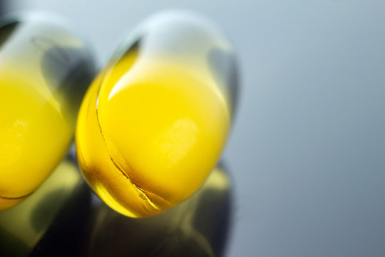 Omega 3 supplement, fish oil yellow capsules on dark background, macro image